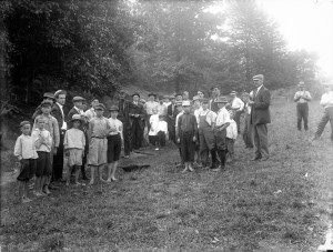 A black and white photograph of a group of children and adults standing in a field.