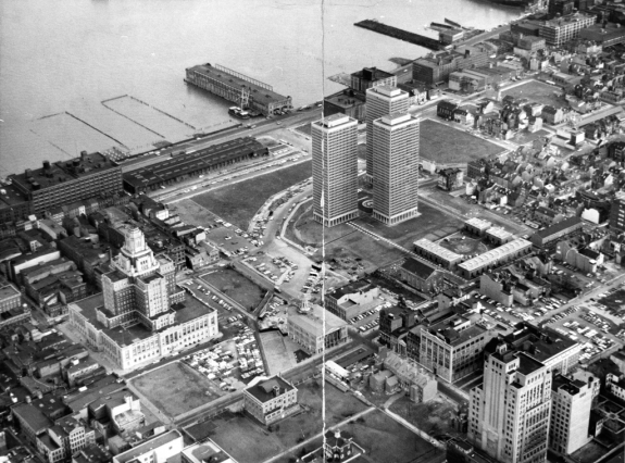 A black and white aerial image of the Society Hill area of Philadelphia. The image shows three large residential towers in the center, with row houses to the around the edges of the image, with a part of the Delaware river towards the top of the image. 