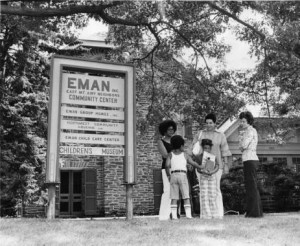 photograph of a group outside a sign for the East Mount Airy Neighbors