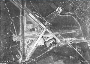 A black and white aerial photograph of the Philadelphia Municipal Airport, showing main building, runways, and fields surrounding the land. 