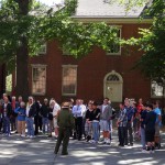 Color photo of a park service ranger speaking to tourists before they begin the Independence Hall tour.
