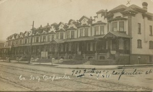 A black and white photograph of rowhomes on 60th Street in Philadelphia, with streetcar tracks visible in the foreground