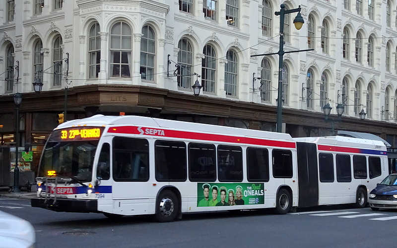 color photograph of one of SEPTA's Diesel Hybrid-Electric buses rolling up Market Street past the Lit Bros building.