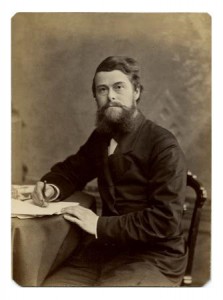 A black and white photograph of Edward Drinker Cope seated at a desk writing