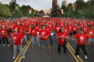 a color photograph of a parade of people wearing red tee shirts dancingdown the Benjamin Franklin Parkway