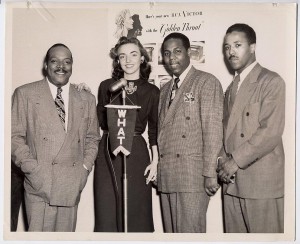 Black and white photograph depicting Jazz legend Count Basie with members of the WHAT staff.