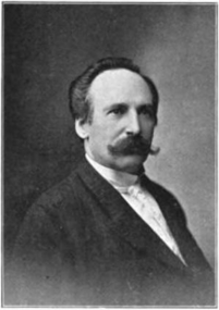 A black and white photograph of inaugural conductor Fritz Scheel, in formal attire with slicked hair and large, characteristic, curly mustache.