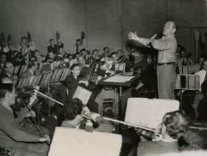 A black and white photograph of Eugene Ormandy conducting the Philadelphia Orchestra at rehearsal with arms eccentrically outstretched.