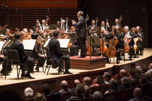 A photograph (taken from the left side of the main floor) of Yannick Nézet-Séguin conducting the Philadelphia Orchestra.