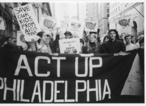 A black and white photograph of HIV/AIDS activists from ACT-UP Philadelphia marching with signs