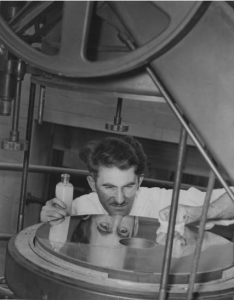 a black and white photograph of Dr. Roy Marshall polishing the Fels Planetarium's giant mirror