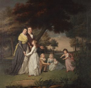 A painting of James Peale and his family, seemingly walking in a park, or at least, through a wooded area near a river (visible at right, near the horizon). He wears a red coat with brass buttons and a white scarf, and walks arm-in-arm beside his wife, Mary Claypoole, who wears a blue and white dress with a yellow shawl wrapped around her body. Four children are also present in the painting. The oldest girl, in a white dress, faces her mother and holds her hand, while a girl in a pink dress (right) dances, and two children, a boy and a girl, sit on the ground (center). The girl holds an infant and the boy wears a black top hat and is holding an apple. A large, leaning, red-leafed tree is directly behind them, with small plants and foliage in the foreground. A cloudy blue sky can be seen in the distance.