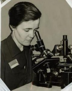 a black and white photograph of Dr. Ruth Patrick looking through a microscope