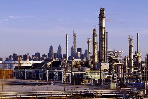 Full color photograph of oil refineries, center city can be seen in the background.