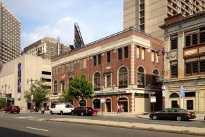 Color photograph of South Broad Street depicting a red brick building at the center.