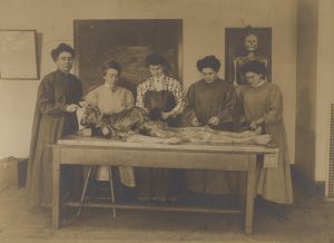 Nineteenth century sepia-toned photograph of five women dissecting a human cadaver.