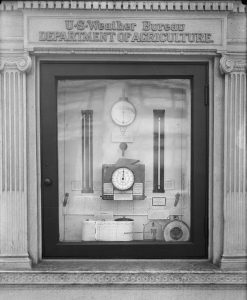 a black and white photograph of a display of weather instruments behind glass