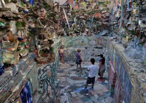 A color photograph of guests exploring the large scale mosaic Philadelphia Magic Gardens by Isaiah Zagar