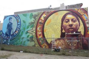 A color photograph of the Aqui y Alla mural of two young Mexican immigrants