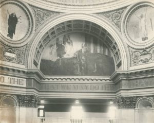 A black and white photograph of one segment of the Pennsylvania capitol building rotunda showing murals under archways