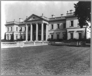 A black and white photograph of a Greek-Revival mansion with a columned portico