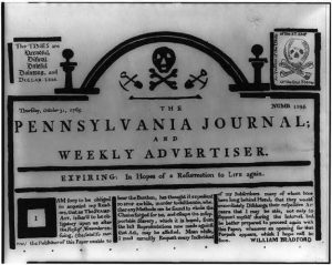 The front page of the Pennsylvania Journal and Weekly Advertiser with two prominent skull and crossbones printed on it, one where the normal header would be and one in the upper left corner. Article text announces that the newspaper is folding due to the cost of the Stamp Act.