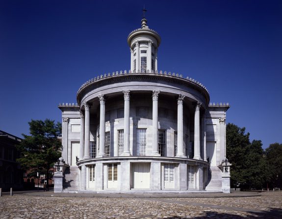 A color photograph of the Merchants' Exchange building showing Greek-style columns on a large front portico.