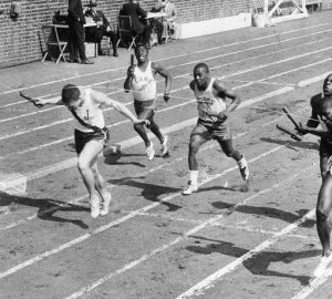 Black and white photograph of high school boys runners crossing the finish line at the Penn Relays.