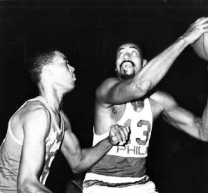 A black and white photograph of Wilt Chamberlain as a 76er playing against the Los Angeles Lakers.