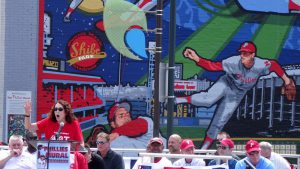 color photo with Phillies mural in background and Mural Arts Program founder Jane Golden speaking foreground.