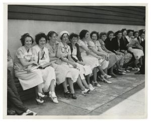 A black and white photograph of women sitting on a bench outside Apex Hosiery during a strike