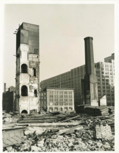 A black and white photograph of a factory being demolished