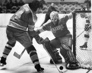 A black and white photograph of goalie Bernie Parent in a Philadelphia Blazers uniform, defending the goal during a game.