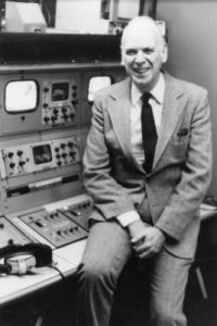 Black and white photograph of Professor John Roberts leaning on studio recording equipment.