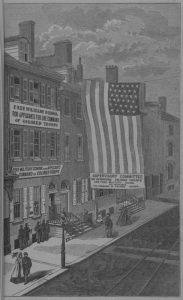 a black and white illustration of the Free Military School for Applicants for Command Command of Colored Troops, held in a large row house. An enormous american flag hangs from the roof to nearly street level near the front entrance. 