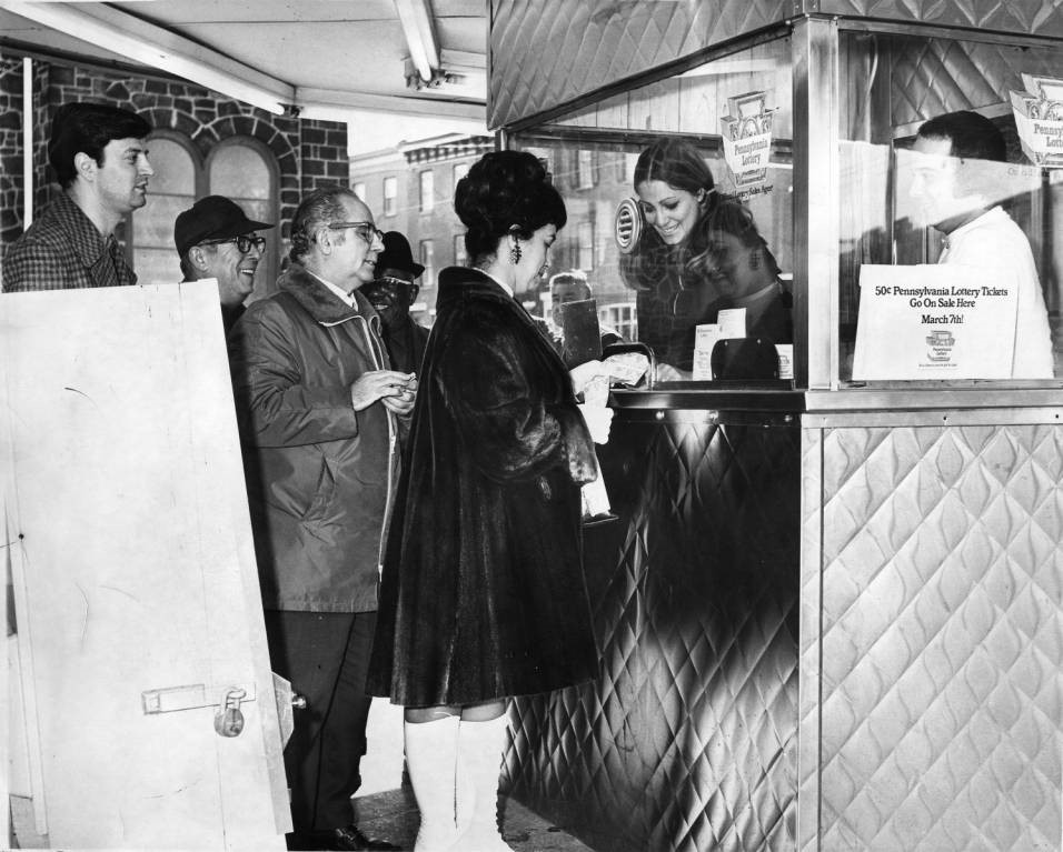 A black and white photograph of a line of people wating to buy lottery tickets from the newly formed Pennsylvania Lottery.
