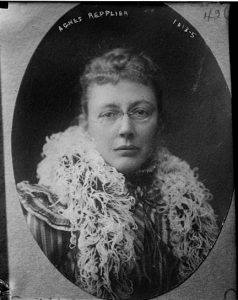 A black and white photograph of Agnes Repplier. She wears an ostrich feather boa and metal framed eyeglasses.