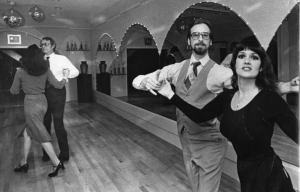 a black and white photogrpah of a couple in a ballroom dancing class