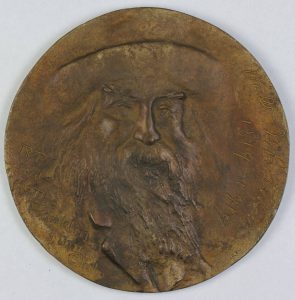 a color photograph of a medal with the likeness of Walt Whitman pressed into it