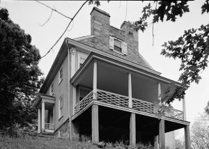 a black and white photograph of the Thomas Leiper estate. It features a prominent porch, columed entryway, and twin chimneys.