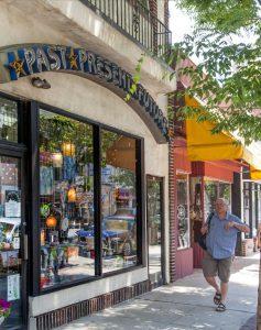 color photo of pedestrian walking past shops in downtown Ardmore, PA