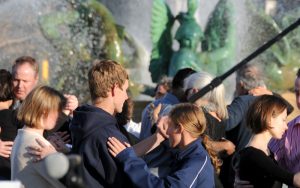 color photo with several couples slow-dancing in foreground with Swann Fountain in background