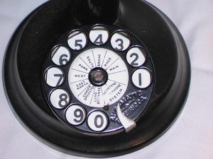 a color photograph of a black rotary telephone dial with white lables