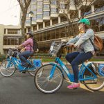 a color photograph of a man and a woman riding blue rental bicycles in Philadelphia.