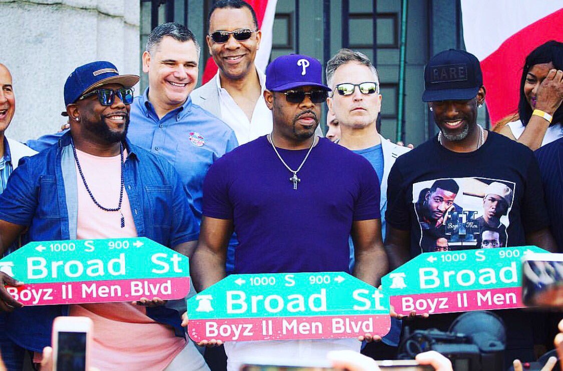 Photograph of Boyz II Men holding street signs