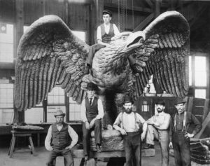 Employees from Tacony Iron Works pose next to a bronze eagle statue they made for City Hall