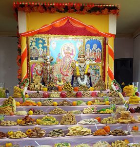 A color photograph of a hindu shrine with many plates of food set out in front of it.