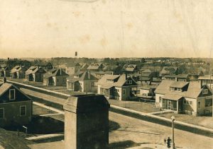 Sepia-toned photograph of a village of one-and-a-half story bungalows.