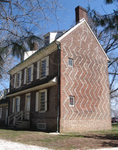 Color photograph of two story, three bay, brick home taken from the front right corner of the building in order to showcase the pattern brick-work on the side of the home.