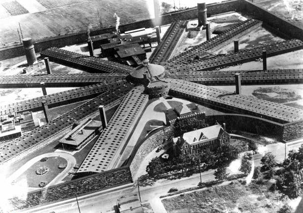 a black and white aerial photograph of Holmsburg Prison. It has ten wings connected in a radial pattern to a central hub and is surrounded by a wall.